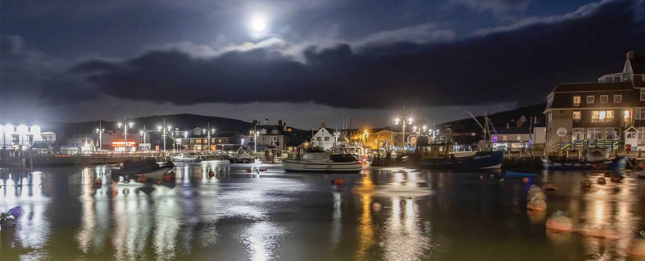 Moonlit West Bay harbour with reflections on the water