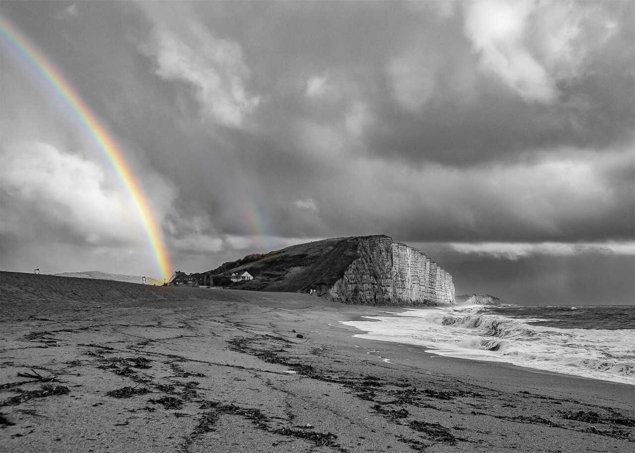 Black and white rainbow scene at West Bay
