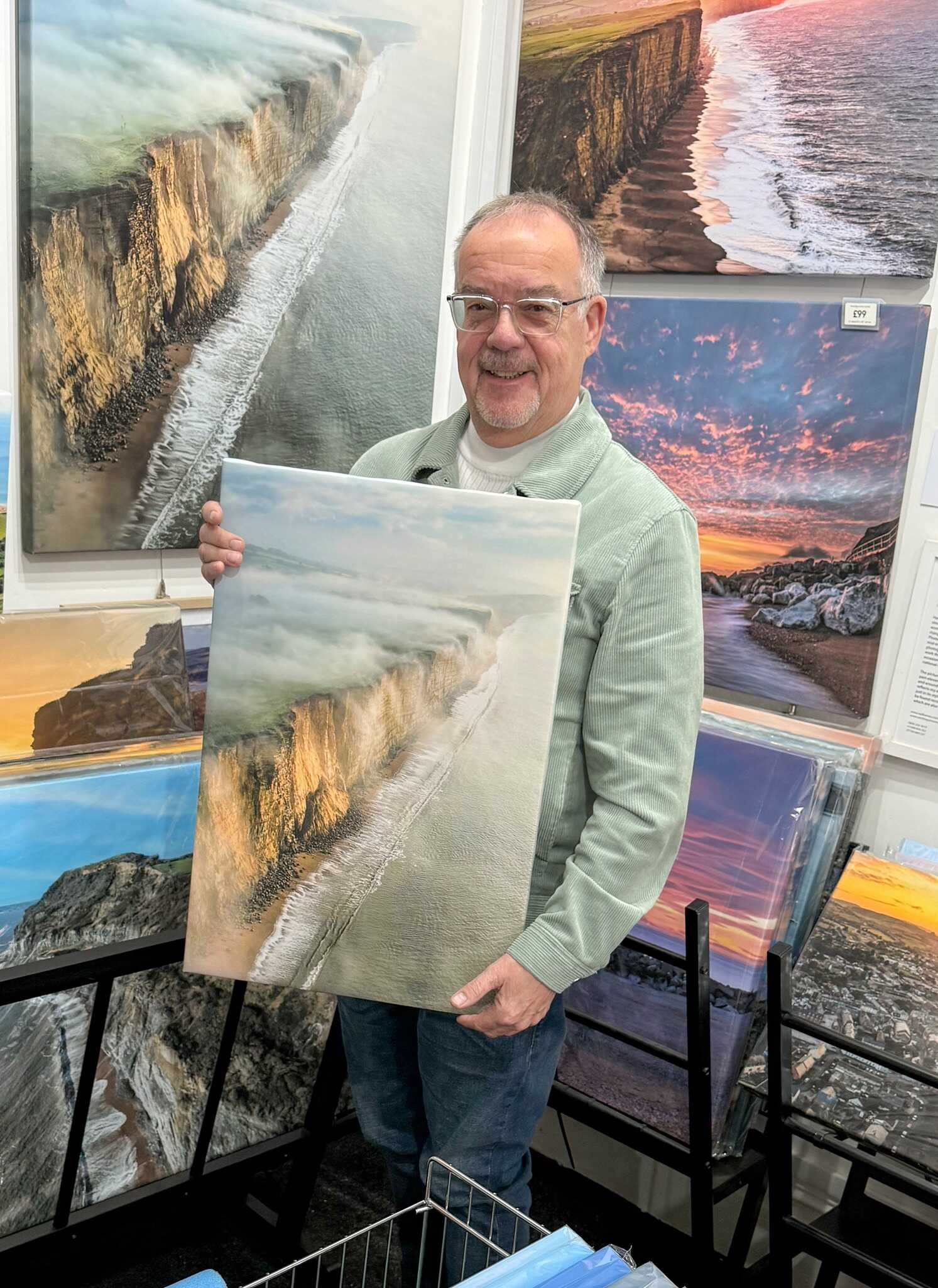 Neil Barnes holding a Dorset coastal photographic print in the Bridport print shop
